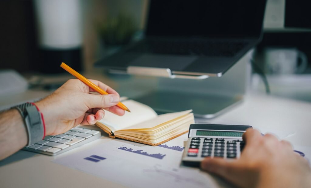 a person sitting at a desk with a calculator and a notebook